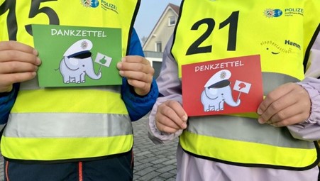 Zwei Kinder halten eine grüne und eine rote Karte in die Kamera. Die grüne Karte wird bei angepasster Geschwindigkeit überreicht, die rote bei zu hoher Geschwindigkeit