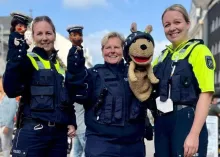 Drei Polizeibeamtinnen stehen in Uniform zur Kamera. Sie tragen auf ihren Armen jeweils Puppen die zur Verkehrserziehung genutzt werden.