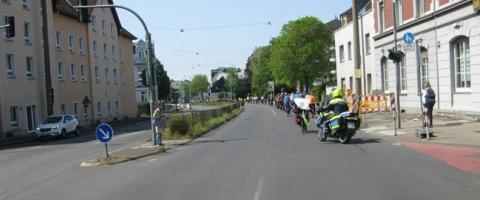 Viele Fahrradfahrer in Reihe auf einer Straße und ein Polizeimotorrad