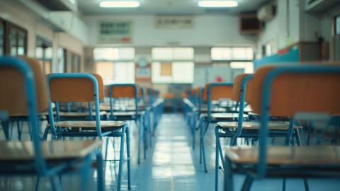 Blick von hinten in einen Klassenraum. Die Stühle sind auf die Tische hochgestellt