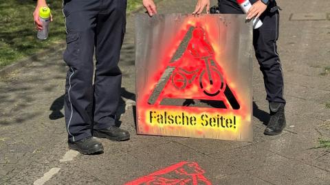 Ein Bild einer benutzten Farb-Schablone mit einem Hinweisschild für Radfahrende