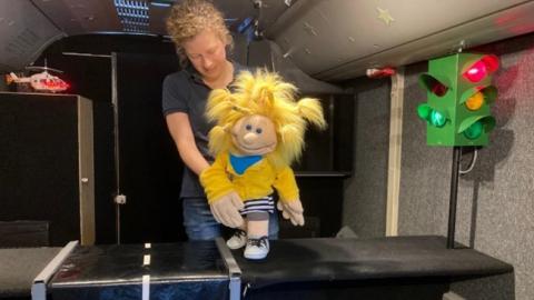 Eine Puppenspielerin hinter der Bühne mit einer Puppe
