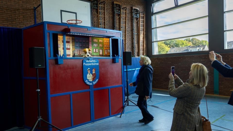 Die Verkehrspuppenbühne der Bonner Polizei ist in einer Turnhalle aufgebaut. Zuschauer stehen davor