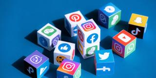 Verschiedene Logos von Social-Media-Angeboten auf Würfeln vor blauem Hintergrund