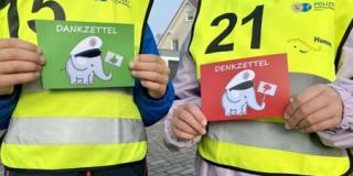 Zwei Kinder halten eine grüne und eine rote Karte in die Kamera. Die grüne Karte wird bei angepasster Geschwindigkeit überreicht, die rote bei zu hoher Geschwindigkeit