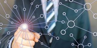 Ein Mensch im Anzug zeigt mit dem Finger auf den Betrachter. An dessen Finger bildet sich ein Netzwerk mit vielen Abzweigungen und Verknüpfungspunkten