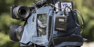 Bild einer TV-Kamera in Nahaufnahme. Die Kamera steckt in einem Regenschutz