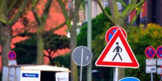 Viele Verkehrsschilder. Das Schild "Vorsicht Fußgänger" im Vordergrund