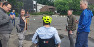 Ein Rollstuhlfahrer auf einer Rampe, daneben weitere Übungsteilnehmende